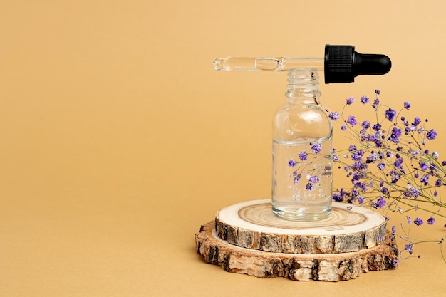 Un podium en bois un brin de gypsophile et une bouteille avec une pipette remplie d'huile ou d'essence d'acide hyaluronique Concept de soins corporels cosmétiques spa naturels