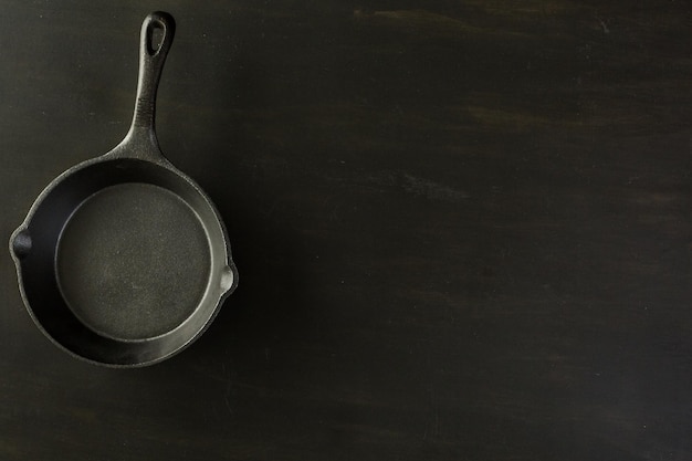 Poêle en fonte traditionnelle sur table en bois noir.