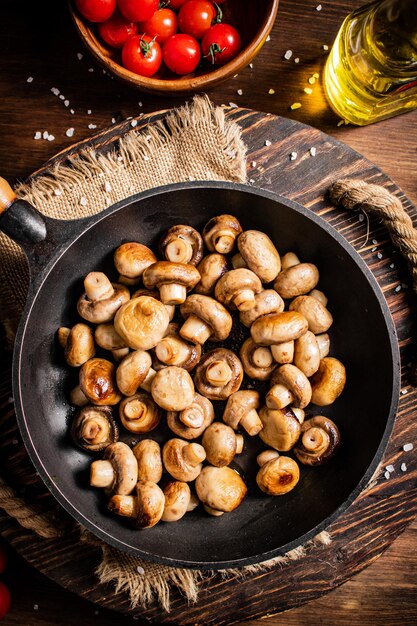 Poêle à frire avec champignons frits sur un plateau en bois