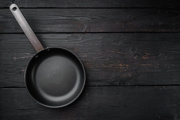 Poêle à frire en fonte avec espace de copie pour le texte ou la nourriture avec espace de copie pour le texte ou la nourriture, vue de dessus à plat, sur fond de table en bois noir