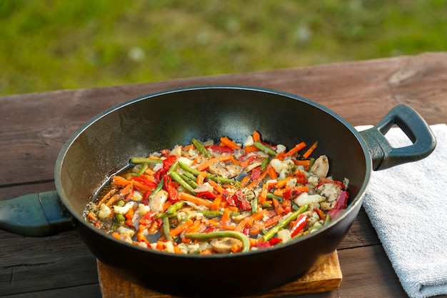 Poêle à frire avec des légumes cuits sur une serviette sur une table en bois