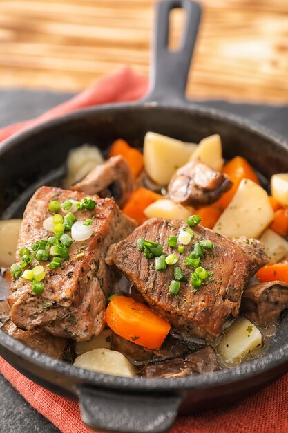 Poêle à frire avec de la viande cuite et des pommes de terre sur la table