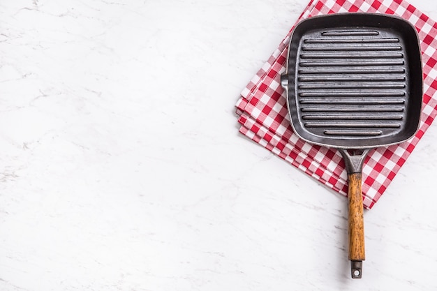 Poêle à griller vide sur table en marbre avec nappe rouge - vue de dessus.