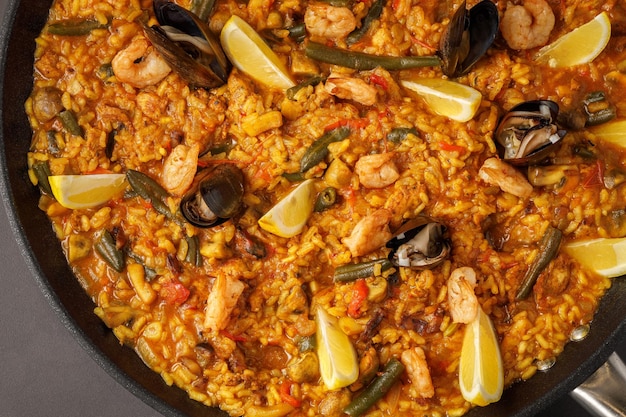 Photo une poêle de paella aux fruits de mer et citrons.