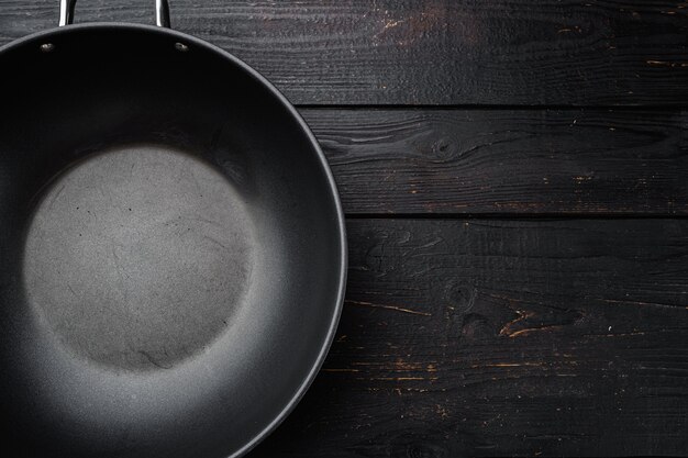 Poêle avec poignée wok avec espace de copie pour le texte ou la nourriture avec espace de copie pour le texte ou la nourriture, vue de dessus à plat, sur fond de table en bois noir