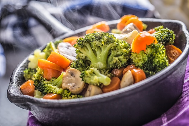 Poêle végétalienne. Nourriture végétarienne - champignons carottes brocoli sel poivre sur beurre.