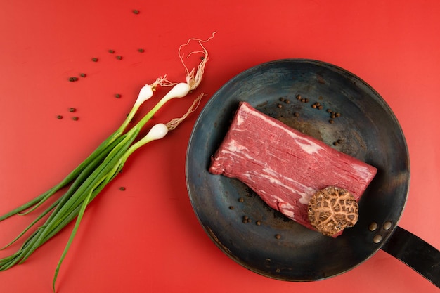 Sur une poêle viande crue divers légumes et épices