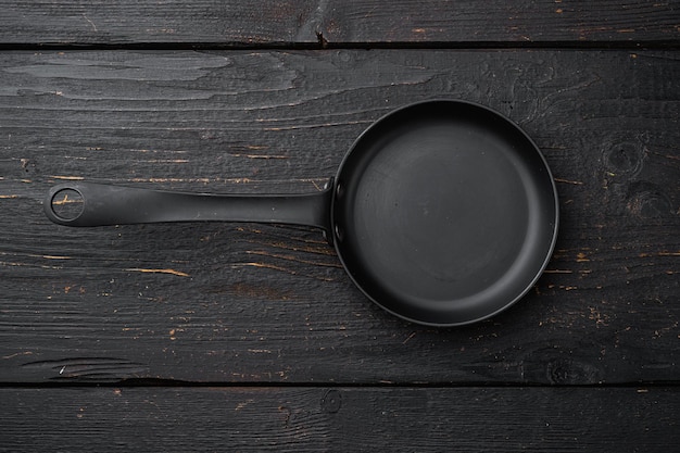 Poêle vide, poêle à frire avec espace de copie pour le texte ou la nourriture avec espace de copie pour le texte ou la nourriture, vue de dessus à plat, sur fond de table en bois noir