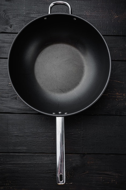 Poêle Wok vide avec espace de copie pour le texte ou la nourriture avec espace de copie pour le texte ou la nourriture, vue de dessus à plat, sur fond de table en bois noir