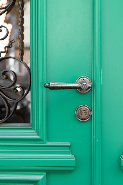 Poignée décorative vintage antique et serrure sur porte en bois vert.