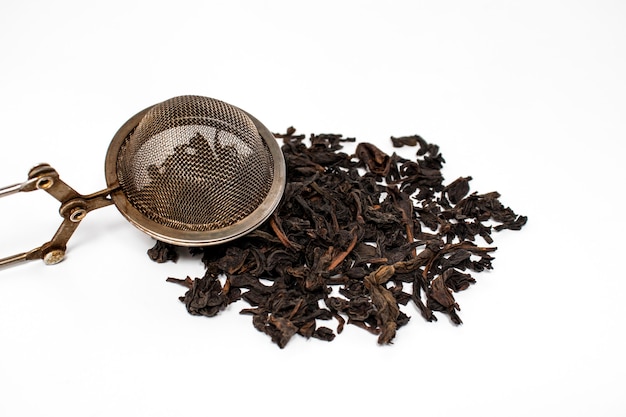 Poignée de feuilles de thé noir sur fond blanc, la boisson est indispensable lorsque l'on a besoin de se réchauffer, mais elle est également excellente sous la chaleur.