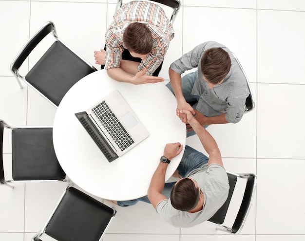 Poignée de main des collègues assis autour de la table le concept de coopération