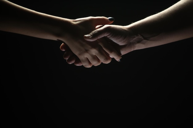 Poignée de main entre les deux partenaires Sauvetage ou aide geste des mains Concept de salut Mains de deux personnes au moment de l'accord de sauvetage aide Isolé sur fond noir