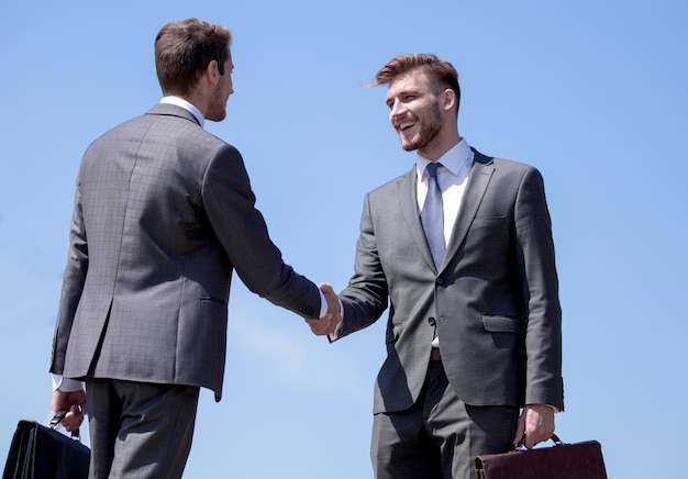 Poignée de main des gens d'affaires sur le fond du ciel