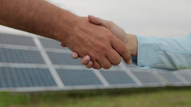 Poignée de main de l'homme et de la femme sur le fond des panneaux solaires. Concept d'énergie verte. Champ de panneaux solaires.