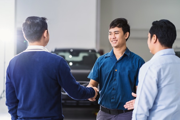 Poignée de main de mécanicien asiatique avec le client et leader du centre de service de maintenance