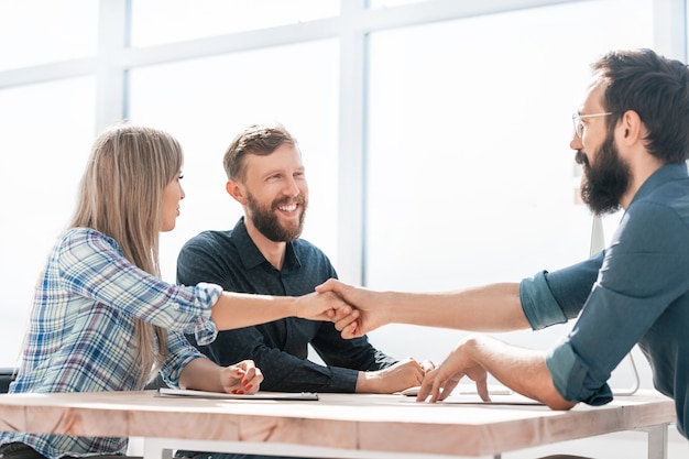 Poignée de main de partenaires commerciaux souriants lors d'une réunion d'affaires.