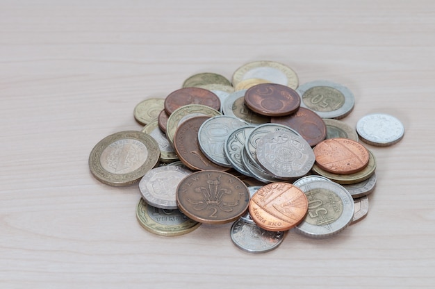 Une poignée de pièces de différents pays, couleurs, dignité et tailles sont dispersées sur la table.