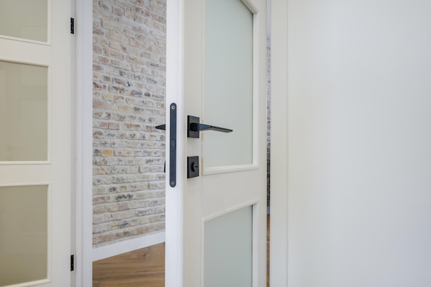 Poignée de porte noire moderne sur une porte en bois blanche à l'intérieur