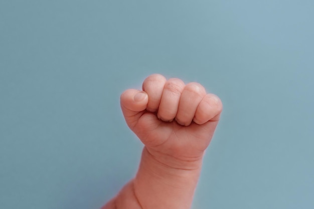 Le poing d'un bébé est tenu sur un fond bleu.