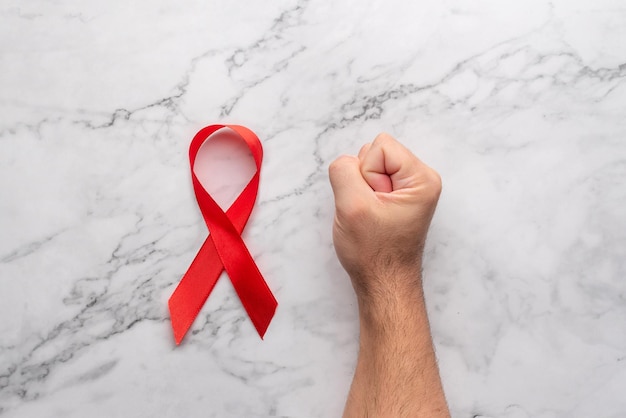 Poing serré sur une table en marbre et ruban rouge Journée mondiale du sida Grève contre la maladie du vih Stop AIDS