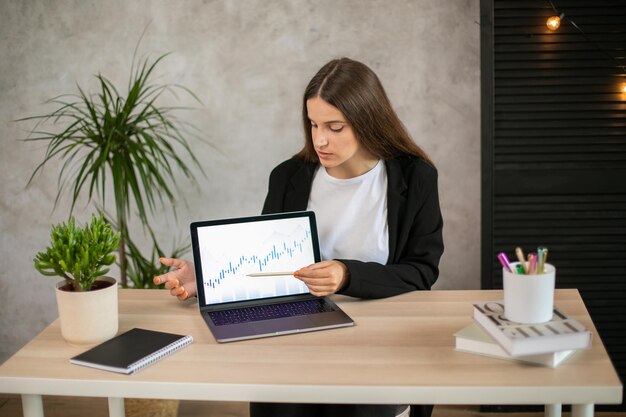 Point de fille au graphique sur ordinateur portable au bureau