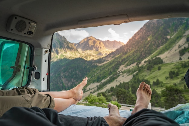 Point de vue des jambes du couple romantique à l'intérieur du vieux van profitant du paysage incroyable ensemble