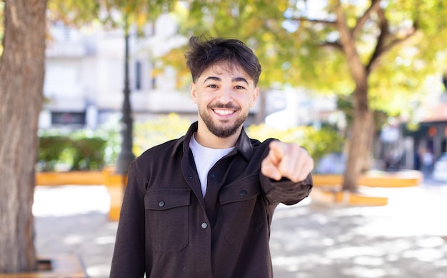 pointant vers la caméra avec un sourire amical confiant satisfait vous choisissant