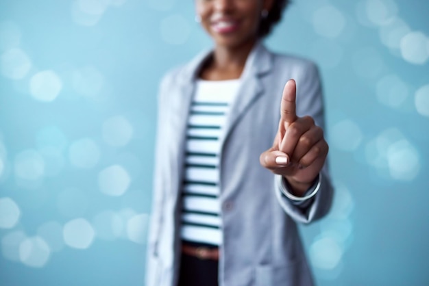 Photo À la pointe de la technologie de pointe. photo recadrée en studio d'une jeune femme d'affaires touchant une interface sur fond bleu.