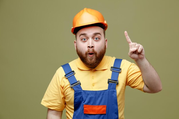 Points impressionnés jusqu'au jeune constructeur homme en uniforme isolé sur fond vert