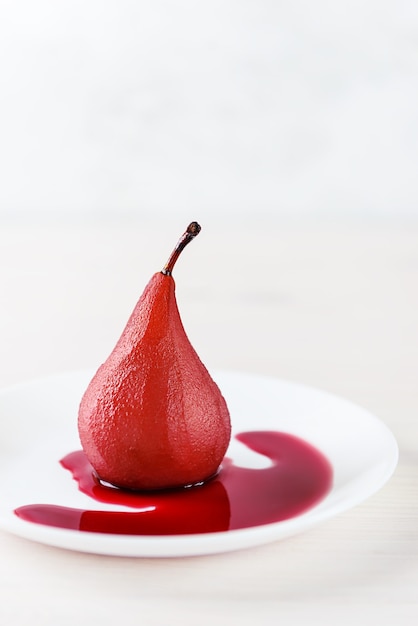 Poire au vin rouge sur une assiette blanche