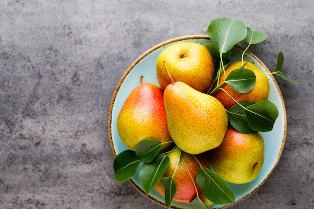 Poire bio fraîche avec des feuilles dans l'assiette