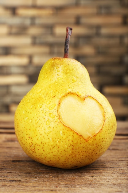 Poire mûre avec coeur sur table en bois, gros plan