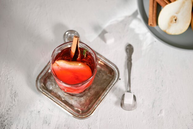 Poire tranchée chaude faite maison avec un bâton de cannelle sur une surface blanche