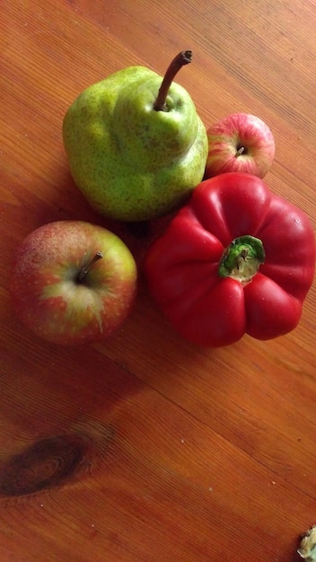 Poire verte deux pommes rouges et poivron rouge sur table en bois