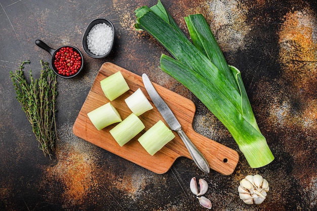 Poireau haché pour la cuisson des poireaux braisés avec des ingrédients d'herbes , sur fond de métal rustique sombre, vue de dessus avec espace pour le texte.