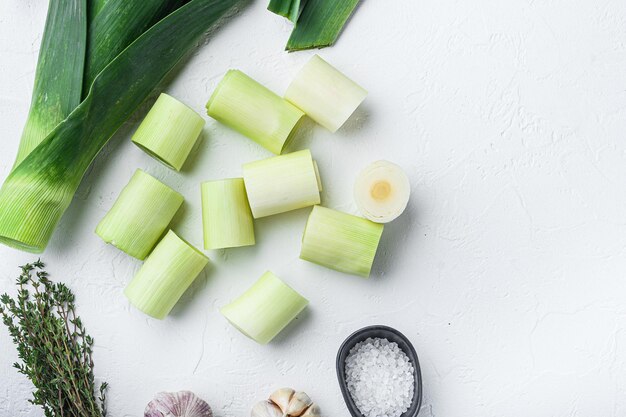 Poireaux hachés crus pour le gril non cuits avec des ingrédients d'herbes, sur la vue de dessus de fond blanc texturé avec un espace pour le texte.