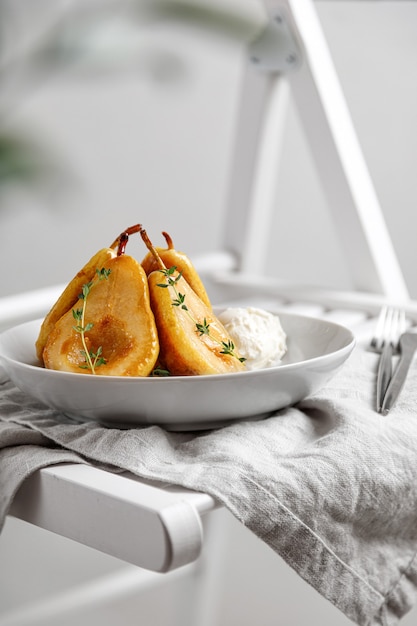 Poires caramélisées dans une assiette de crème glacée sur une serviette sur une chaise en gros plan