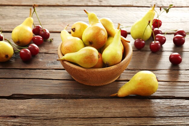 Photo poires mûres et cerises sur table en bois se bouchent