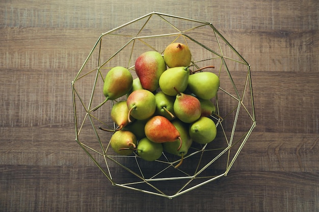 Poires mûres dans un bol de fruits en métal sur une table en bois