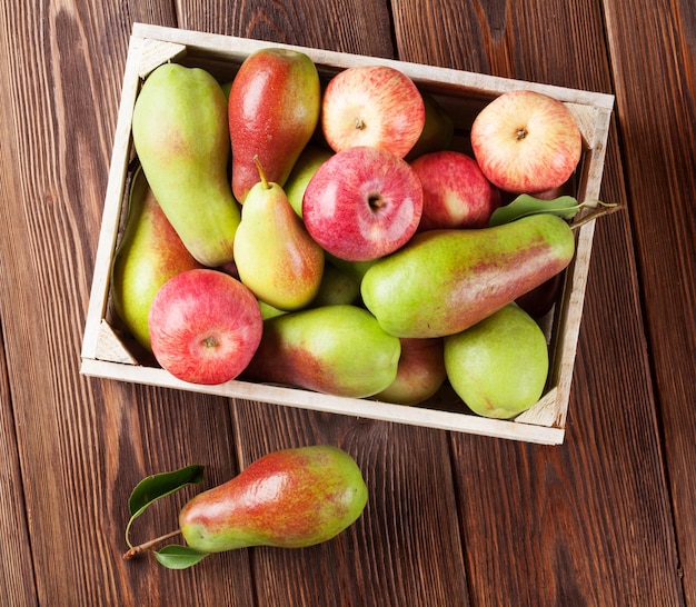 Poires et pommes dans une boîte en bois sur table