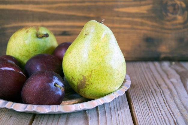 Poires et prunes sur un fond en bois.