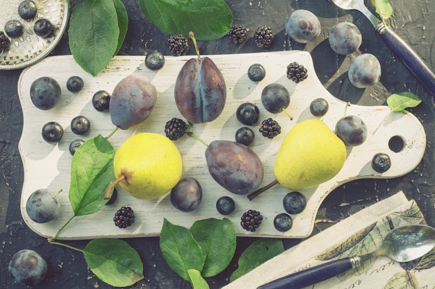 Poires et prunes sur une planche de cuisine blanche