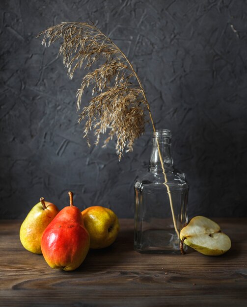 Photo poires rouges et une carafe sur un fond sombre