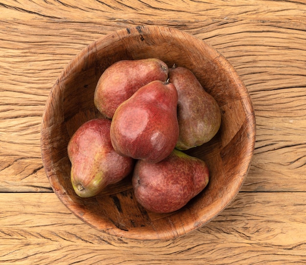 Poires rouges dans un bol sur une table en bois