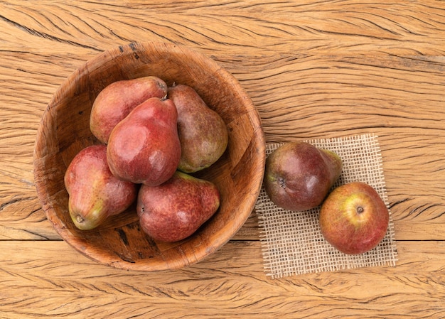 Poires rouges dans un bol sur une table en bois