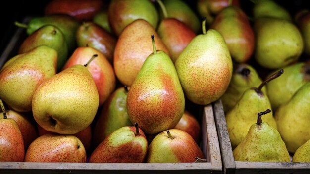 Poires rouges jaunes mûres dans des caisses en bois vendues au supermarché