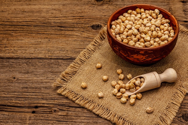 Pois chiche sec dans un bol en céramique sur une vieille table en bois. Ingrédient traditionnel pour la cuisson du houmous