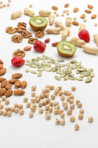 Pois chiches, amandes, noix et fruits pour un petit-déjeuner énergétique. Surface blanche. Vue d'en-haut.