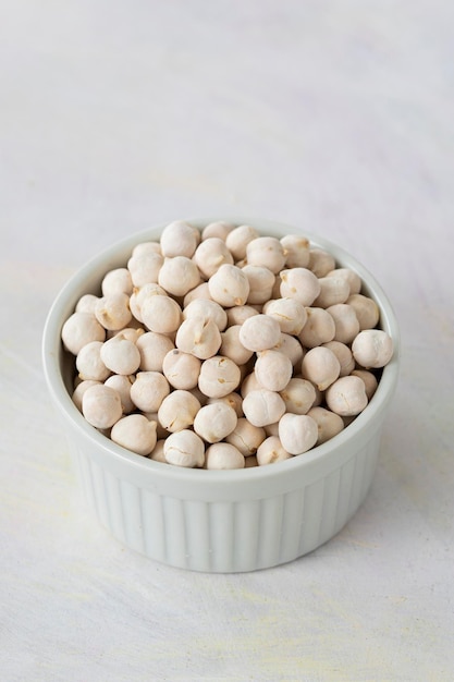 Pois chiches blancs dans un bol sur fond de bois blanc